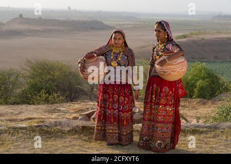 Zwei Ahir Frauen in traditionellen bunten Tuch mit Wasser in einem Tongefäß Kanne, tolle Rann von Kutch Wüste, Gujarat, Indien. Stockfoto