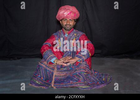 Mann Mitglied der Dhebariya Rabari Gemeinschaft in traditionelle bunte Tuch trägt einen roten Turban, große Rann von Kutch Wüste, Gujarat, Indien. Stockfoto