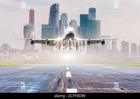 Verkehrsflugzeug Jetliner nähert sich für die Landung auf Start- und Landebahn, moderne Stadt im Hintergrund Stockfoto