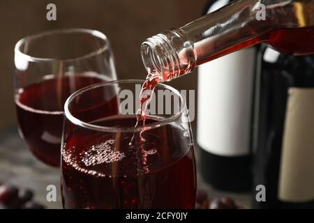 Wein wird aus einer Flasche in Glas auf Holztisch gegossen, close up Stockfoto