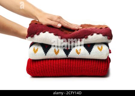 Weibliche Hände halten Haufen Pullover, isoliert auf weißem Hintergrund Stockfoto