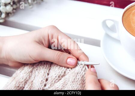 Frau, die vor dem Haus strickt. Handwerkliches Ertragskonzept. Erholung und Entspannung für Frauen. Stricken auf einem hellen Hintergrund. Weibliche Hände, Stricken Knie Stockfoto