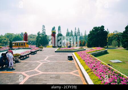 Bogor, Indonesien - EIN Blick auf den blühenden Park Taman Bunga Nusantara an einem bewölkten Nachmittag mit Blick auf einen fast leeren Weg, eine gelbe Straßenbahn. Stockfoto