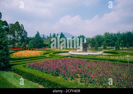 Bogor, Indonesien - EIN Blick auf den Blumen-Themenpark Taman Bunga Nusantara an einem bewölkten Nachmittag mit Blick auf einen Wasserbrunnen in der Mitte eines Flo Stockfoto