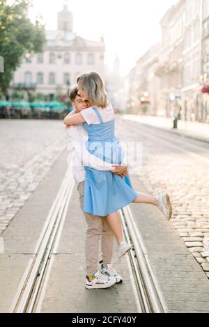 Liebenswert Paar in der Liebe, genießen ihren Spaziergang an einem sonnigen Tag in der Stadt, stehen auf der Straßenbahnlinie. Handsome Kerl hält seine attraktive junge girldriend im Stockfoto