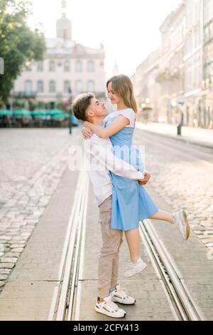 Liebenswert Paar in der Liebe, genießen ihren Spaziergang an einem sonnigen Tag in der Stadt, stehen auf der Straßenbahnlinie. Handsome Kerl hält seine attraktive junge girldriend im Stockfoto