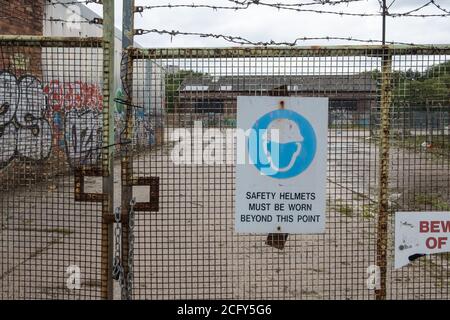 Schild am Zaun auf der Baustelle mit der Aufschrift: Sicherheitshelme müssen über diesen Punkt hinaus getragen werden Stockfoto