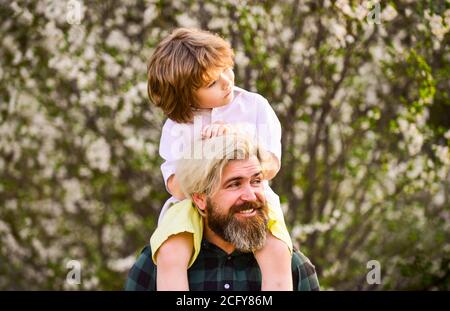 Frohe Familie. Vatertag. Kind, das Spaß mit Papa hat. Kleiner Junge und Vater im Hintergrund Natur. Frühling. Hipster Huckepack Baby. Bärtiger brutaler Mann guter Vater. Vater und Sohn. Bester Vater aller Zeiten. Stockfoto