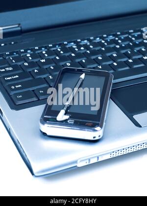 Handy und Stift auf Laptop Stockfoto