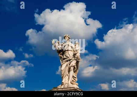 Engelsstatue, die die Nägel Jesu hält Kreuz zwischen Wolken. Ein barockes Meisterwerk aus dem 17. Jahrhundert an der Spitze der Sant'Angelo Brücke im Zentrum von Rom Stockfoto