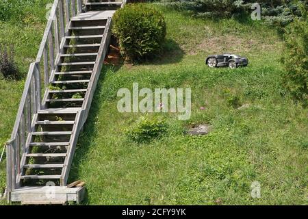 Roboter-Rasenmäher, der Gras an steilem Gefälle schneidet Stockfoto