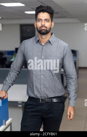 Porträt eines hübschen jungen indischen Geschäftsmannes, der lässig in die Kamera schaut. Unternehmensumgebung. Stockfoto
