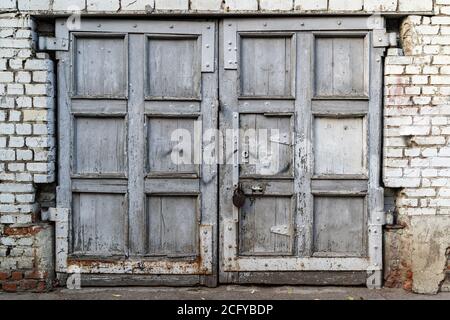Fassade eines verlassenen Gebäudes. Altmodische Eingangstür in schmutzigen weißen und grauen Farben. Stockfoto