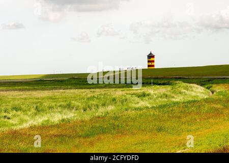 Blick auf Pilsum Leuchtturm in Ostfriesland mit Touristen zu Fuß Rund um den Deich und Fotografieren Stockfoto