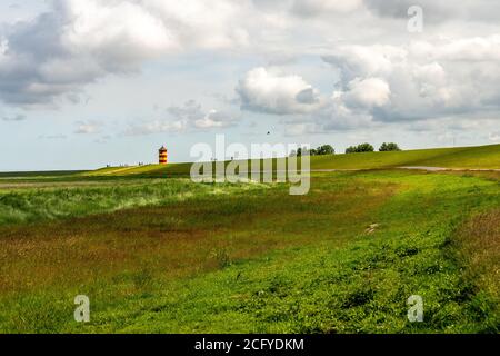 Blick auf Pilsum Leuchtturm in Ostfriesland mit Touristen zu Fuß Rund um den Deich und Fotografieren Stockfoto
