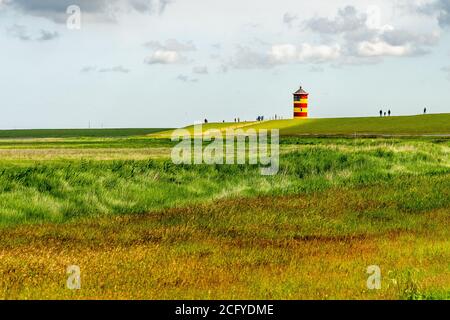 Blick auf Pilsum Leuchtturm in Ostfriesland mit Touristen zu Fuß Rund um den Deich und Fotografieren Stockfoto