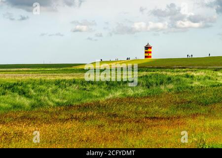 Blick auf Pilsum Leuchtturm in Ostfriesland mit Touristen zu Fuß Rund um den Deich und Fotografieren Stockfoto
