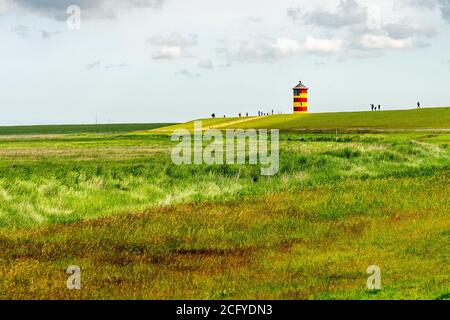 Blick auf Pilsum Leuchtturm in Ostfriesland mit Touristen zu Fuß Rund um den Deich und Fotografieren Stockfoto