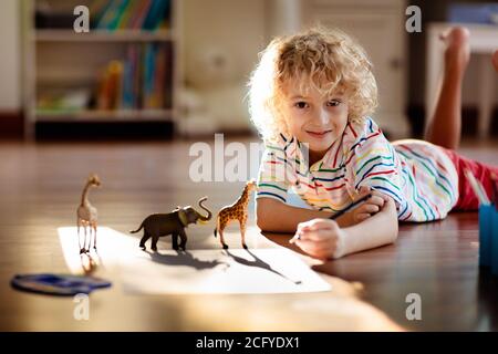 Kind Schatten Zeichnung Tiere. Kinder spielen zu Hause. Fun Basteln für Kindergartenkinder. Kleiner Junge, der Giraffe und Elefanten in einem sonnigen Schlafzimmer malt. Spiel Stockfoto