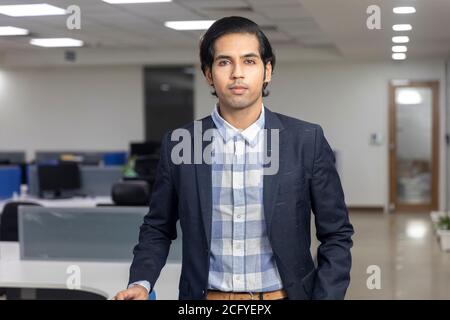 Porträt eines hübschen jungen indischen Geschäftsmann steht vor Corporate Office Hintergrund. Stockfoto