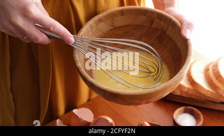 Weibliche Hände Rühreier in einer Schüssel. Frau, die beim Frühstück kocht Stockfoto