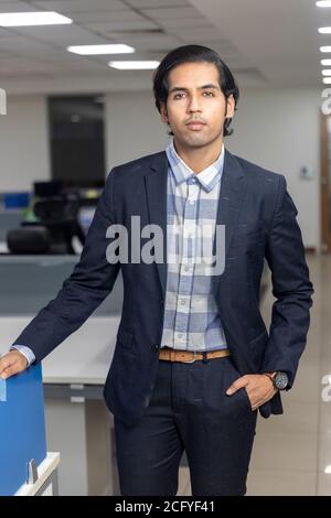 Porträt eines hübschen jungen indischen Geschäftsmann steht vor Corporate Office Hintergrund. Stockfoto