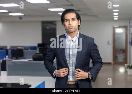 Porträt eines hübschen jungen indischen Geschäftsmann steht vor Corporate Office Hintergrund. Stockfoto