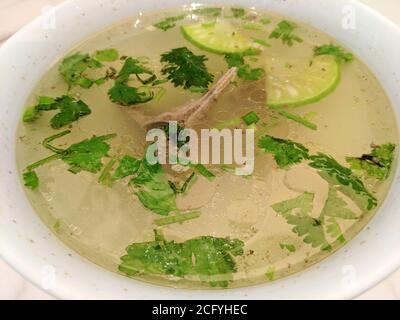 Lammsuppe mit grünem Gemüse in weißer Schüssel unter hell Leicht Stockfoto