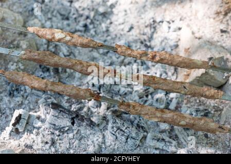 Nahaufnahme, Schweinefleisch lula Kebab auf Spieße, Grill Fleisch auf dem Grill, Lagerfeuer, Kohlen. Schädliche köstliche Lebensmittel Lula Kebab, georgische Gericht auf dem Plateau. Stockfoto