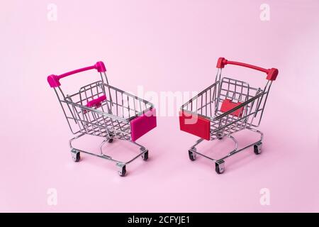 Shopping, Käufe, Supermarkt, Verkauf, Einkaufszentrum Konzept. Zwei leere Metall kleine Miniatur-Spielzeug-Shopping-Trolley auf hellem Hintergrund. Selektiver Fokus Stockfoto