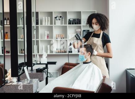 Friseur Trocknen von Haar männlichen Kunden, die beide Einhaltung von Sicherheitsmaßnahmen Stockfoto