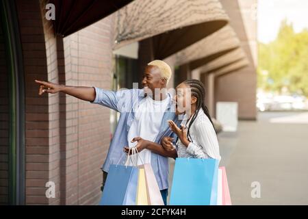 Unglaublicher Ausverkauf. Schockiert afroamerikanischen Jungen und Mädchen schaut in Schaufenster Stockfoto