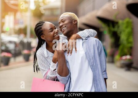 Happy african american Mädchen Umarmungen Mann mit Farbe Taschen in der Nähe Geschäfte Stockfoto