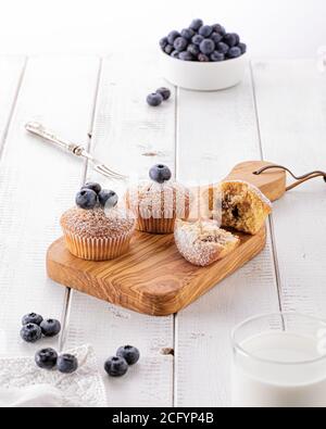 Frisch gebackene Blaubeer Muffins auf Holzbrett auf einem weißen Holztisch im Morgenlicht Stockfoto