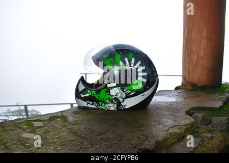 'Yellapur, Karnataka/Indien - 12/08/2020 : EIN Fahrradhelm auf nassem Betonsockel gehalten mit Nebel über dem Hintergrund' Stockfoto