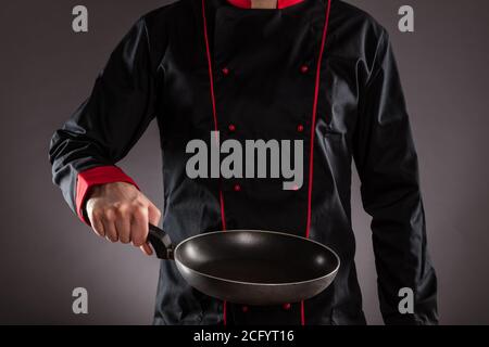 Nahaufnahme des Chefkochs mit leerer Bratpfanne. Konzept der Lebensmittelzubereitung, bereit für die Produktplatzierung. Stockfoto
