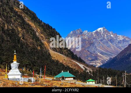 Tibetische Stupa und Gebetsfahne mit hohen Bergketten in Der Hintergrund hinten beleuchtet mit Sonne im Tal von Blumen in Sikkim Indien Stockfoto