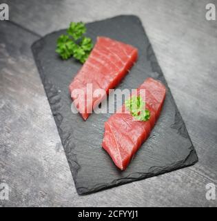 Rohes Thunfischfilet auf schwarzem Steingrund Stockfoto