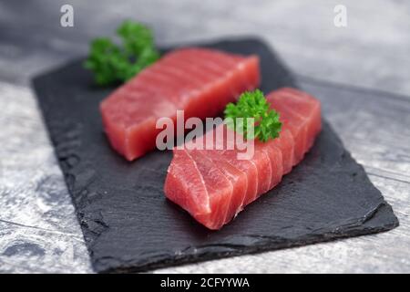 Rohes Thunfischfilet auf schwarzem Steingrund Stockfoto