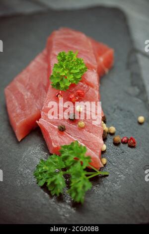 Rohes Thunfischfilet auf schwarzem Steingrund Stockfoto