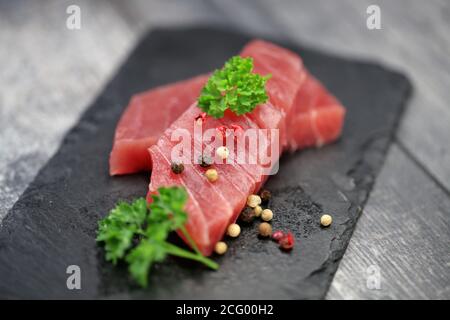 Rohes Thunfischfilet auf schwarzem Steingrund Stockfoto