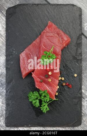 Rohes Thunfischfilet auf schwarzem Steingrund Stockfoto