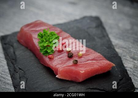 Rohes Thunfischfilet auf schwarzem Steingrund Stockfoto