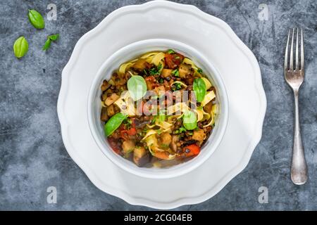 Linsen- und Auberginenragu mit Tagliatelle-Pasta und frischem Basilikum - gesundes vegetarisches Essen Stockfoto