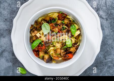 Linsen- und Auberginenragu mit Tagliatelle-Pasta und frischem Basilikum - gesundes vegetarisches Essen Stockfoto