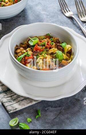 Linsen- und Auberginenragu mit Tagliatelle-Pasta und frischem Basilikum - gesundes vegetarisches Essen Stockfoto