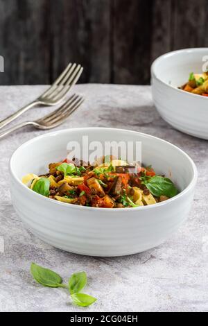 Linsen- und Auberginenragu mit Tagliatelle-Pasta und frischem Basilikum - gesundes vegetarisches Essen Stockfoto