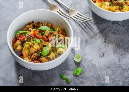 Linsen- und Auberginenragu mit Tagliatelle-Pasta und frischem Basilikum - gesundes vegetarisches Essen Stockfoto