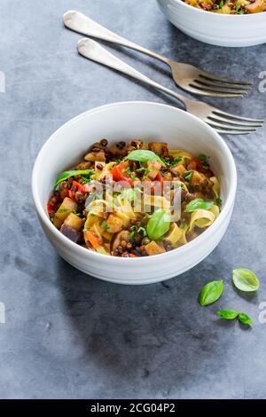 Linsen- und Auberginenragu mit Tagliatelle-Pasta und frischem Basilikum - gesundes vegetarisches Essen Stockfoto