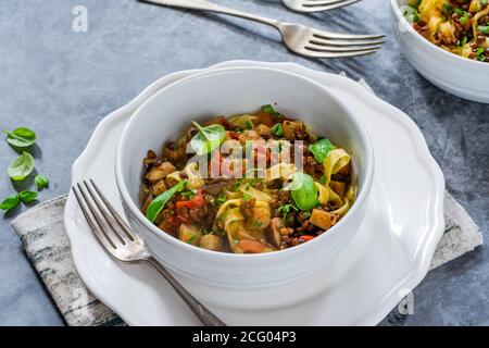 Linsen- und Auberginenragu mit Tagliatelle-Pasta und frischem Basilikum - gesundes vegetarisches Essen Stockfoto